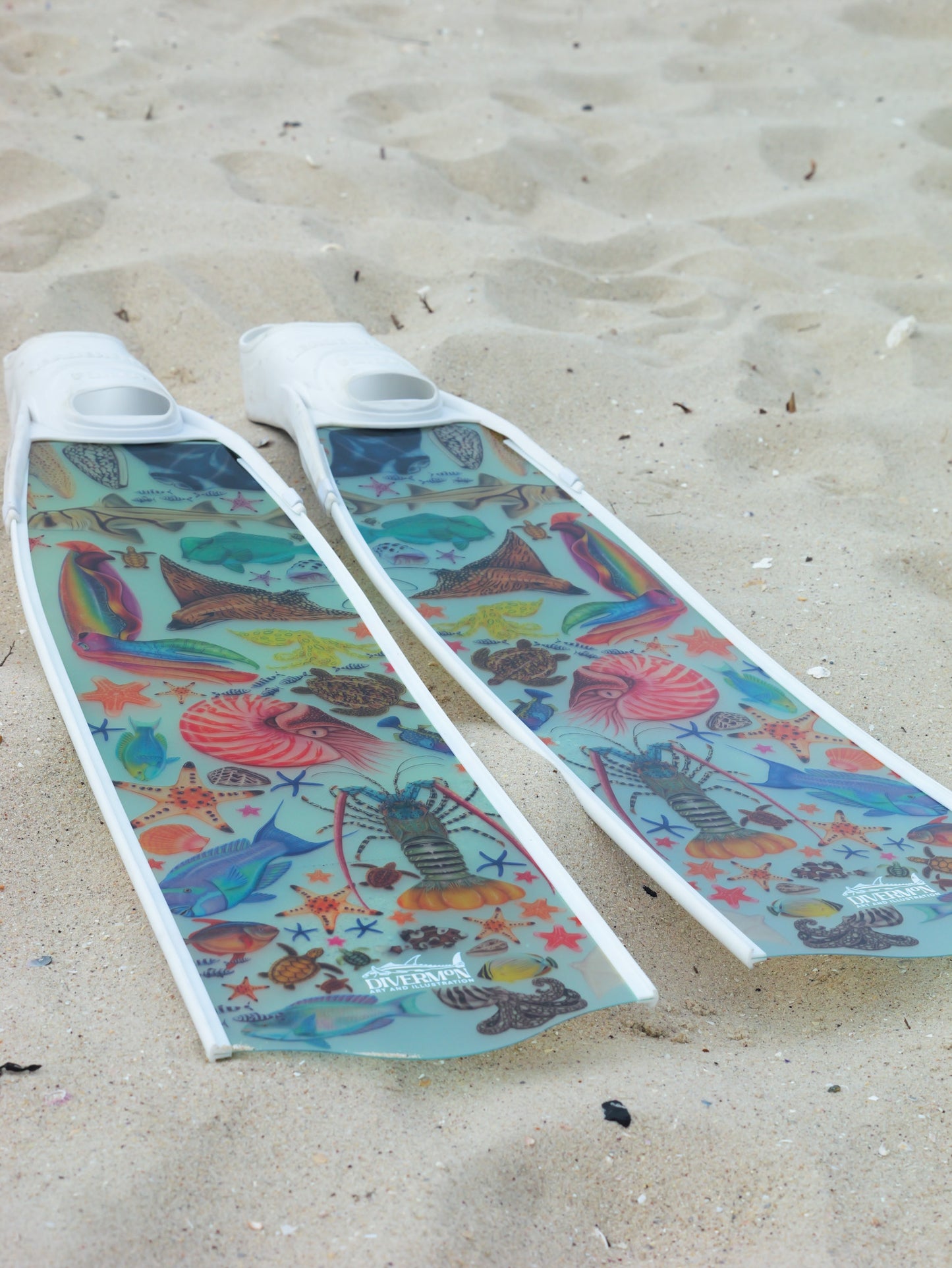 Colourful women freediving fins with sea-themed design on a sandy background