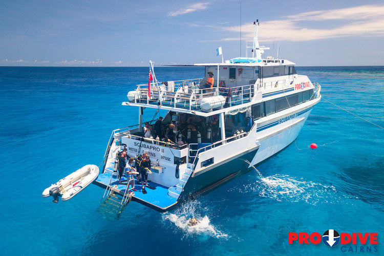 Dive boat with divers in the water on a clear blue day from Pro Dive Cairns