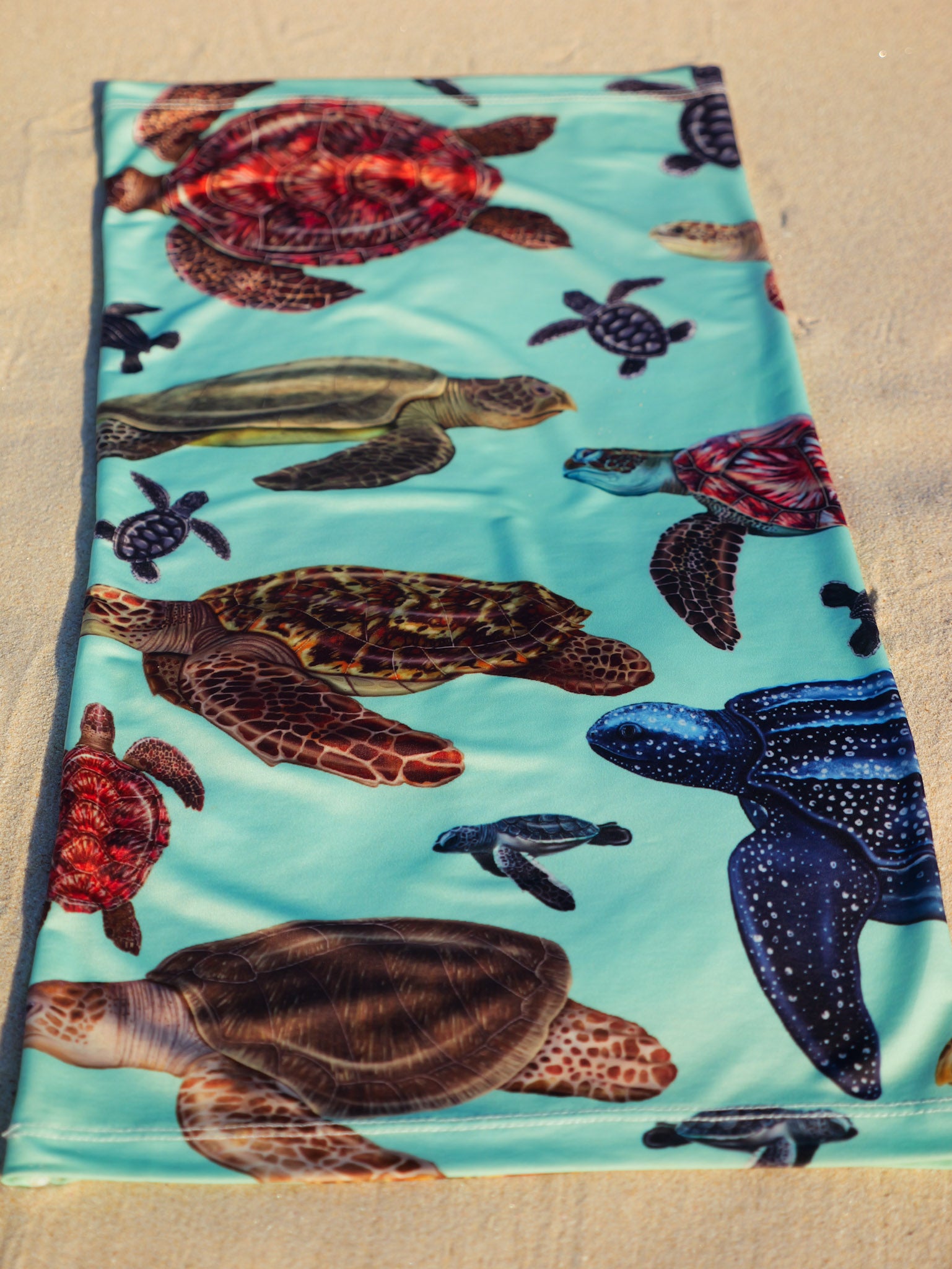 Big turtles green UV gaiter buff design shown laid out close up in great detail sand background made from recycled polyester-spandex ocean illustration by Diver Mon Art 