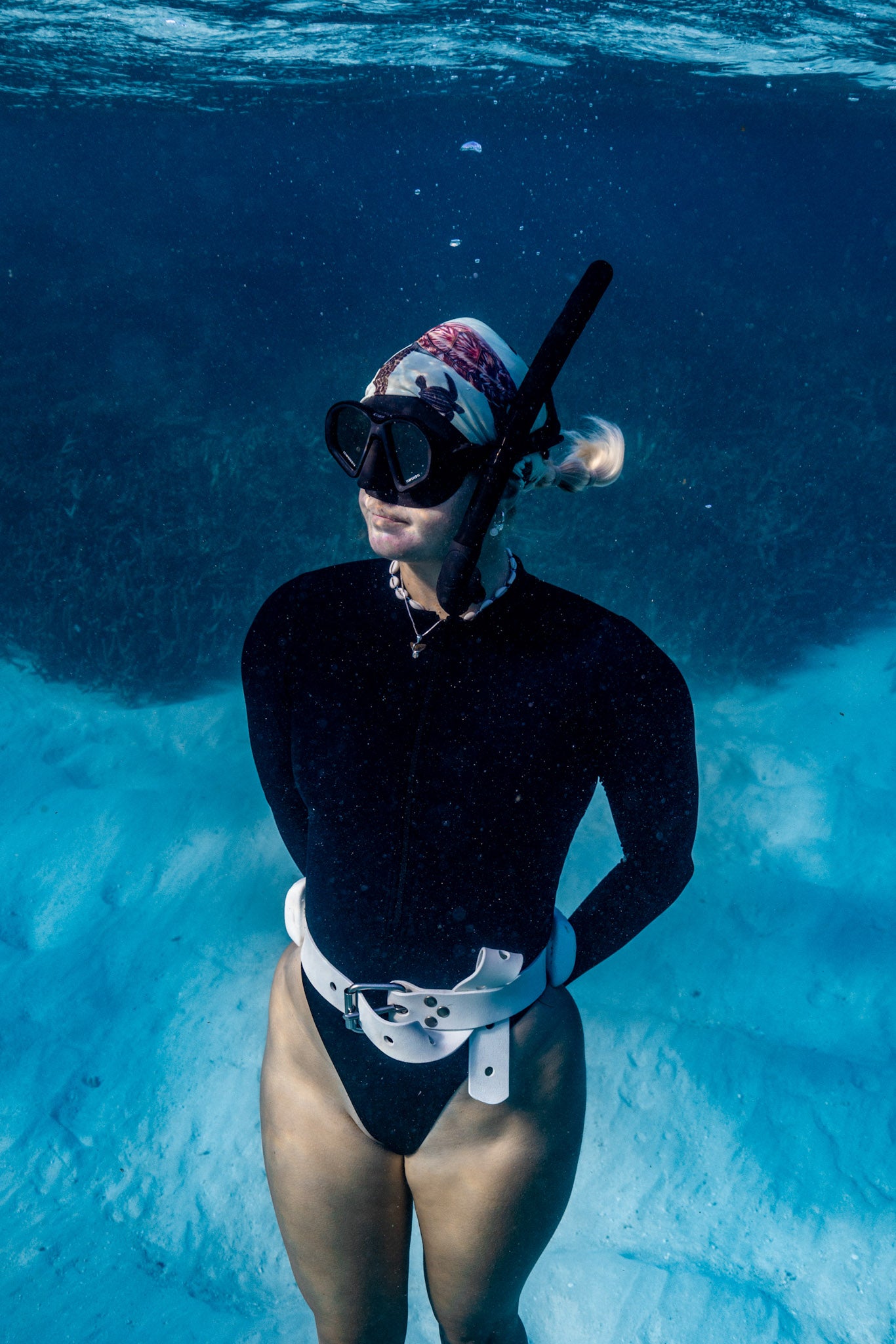 Blonde haired women shown underwater clear blue water wearing big turtles green UV gaiter buff design made from recycled polyester-spandex ocean illustration by Diver Mon Art