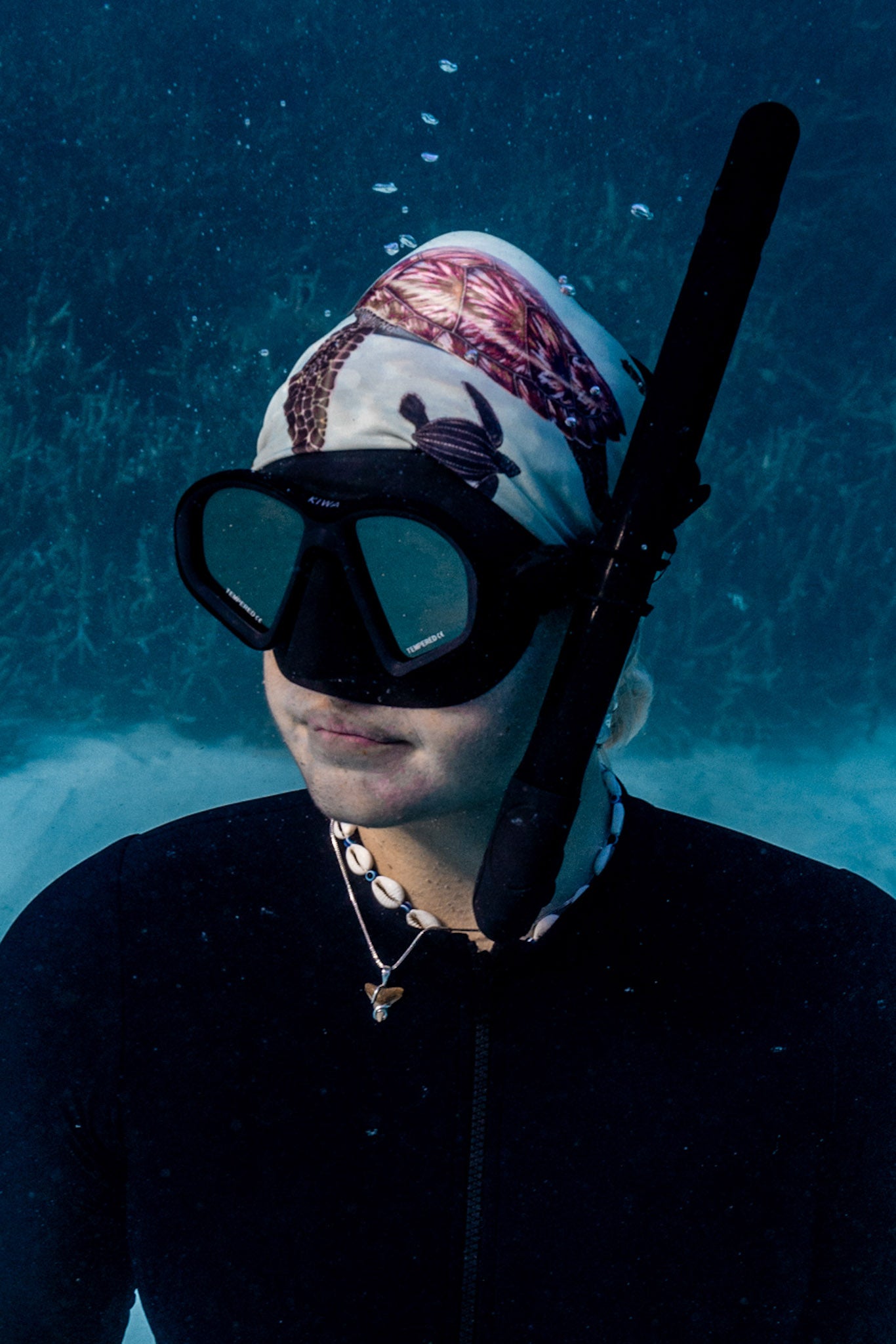 Blonde haired women shown close up great detail underwater clear blue water wearing big turtles green UV gaiter buff design made from recycled polyester-spandex ocean illustration by Diver Mon Art