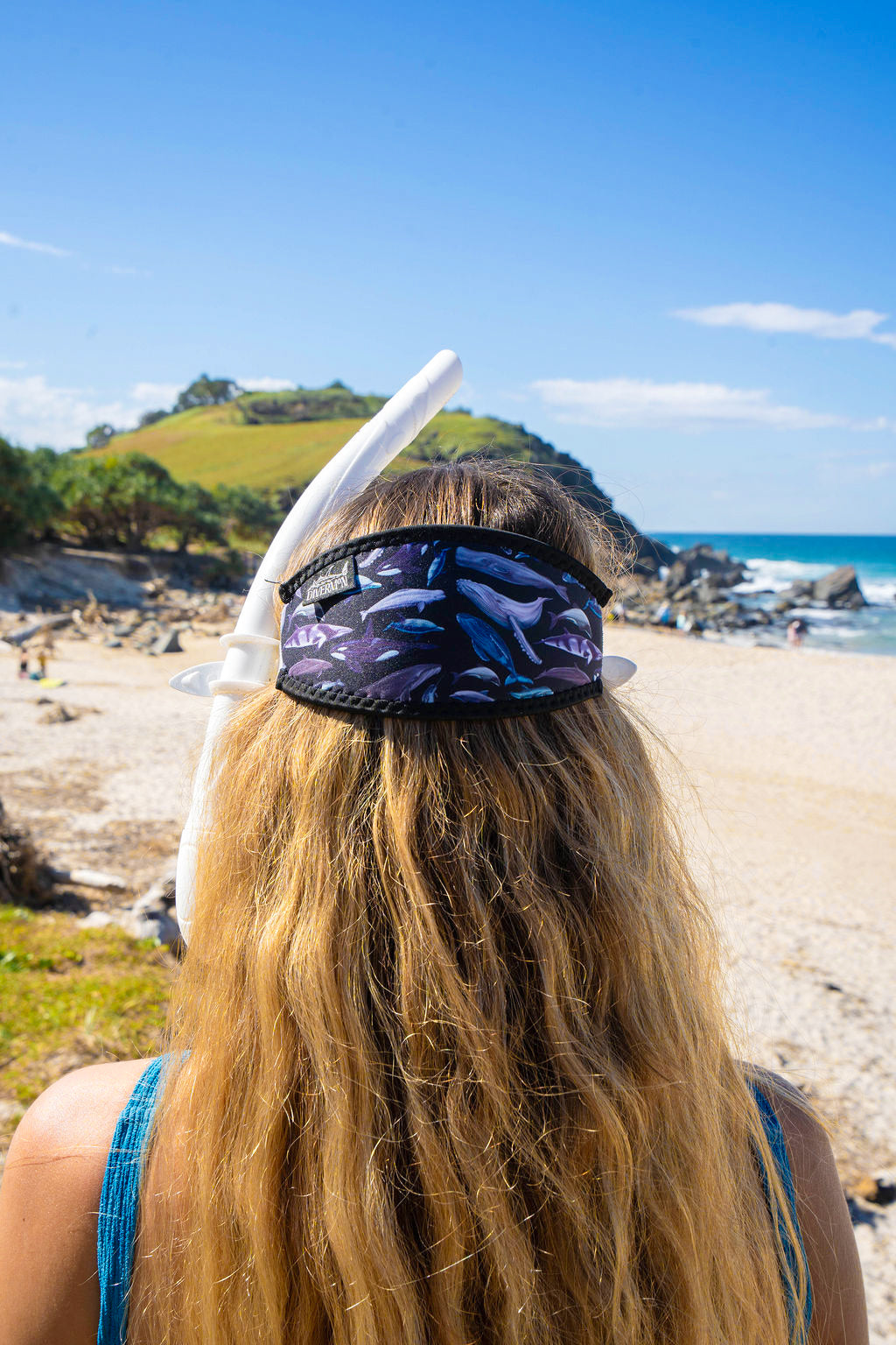 Blonde haired woman seen close up from behind at the beach with the Dolphins, whales and porpoises with a black background neoprene mask strap tamer ocean illustration by Diver Mon Art 
