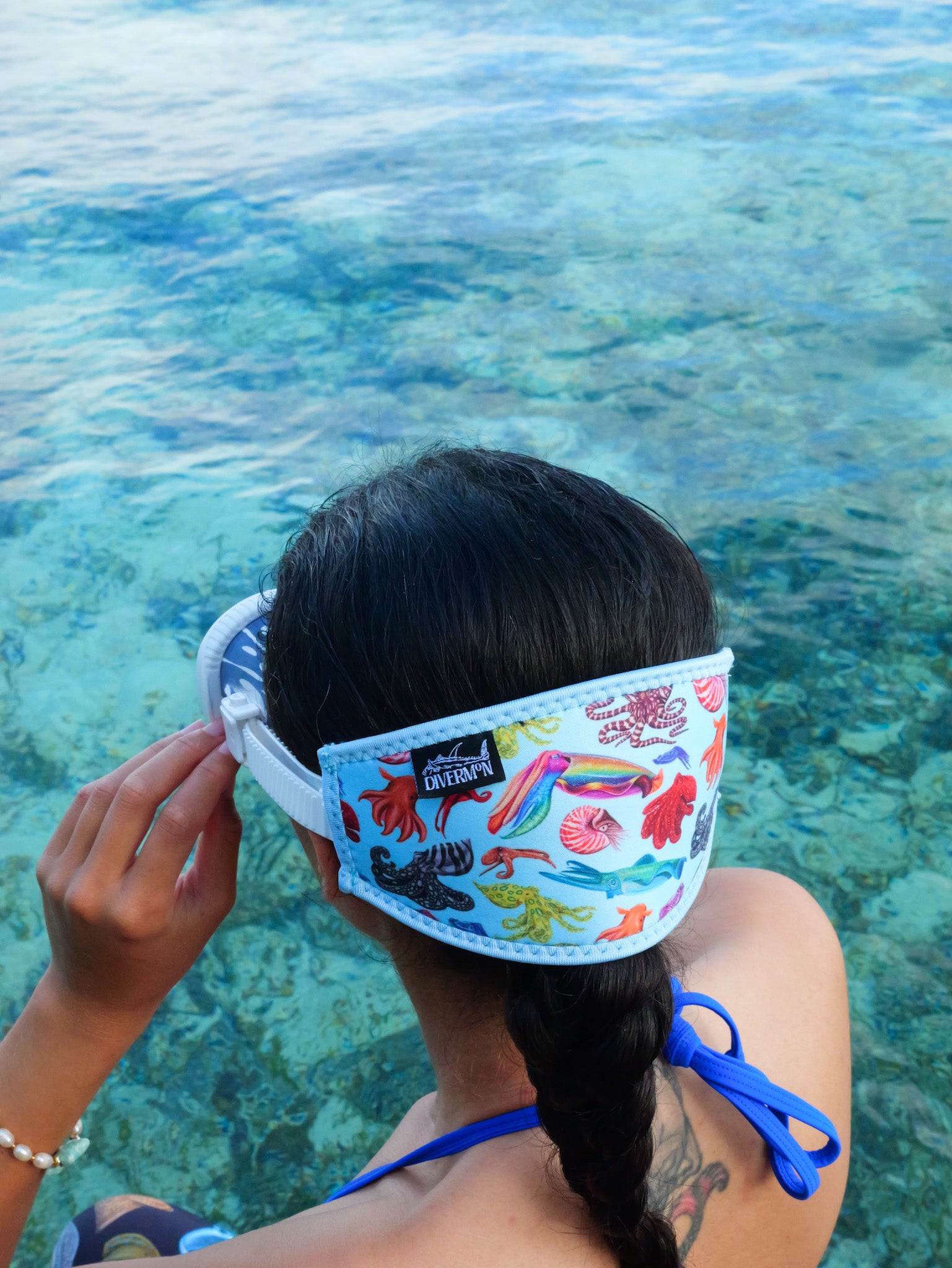 Dark haired woman shown from behind in blue clear water close up with the cephalopod with a light blue background neoprene mask strap tamer ocean illustration by Diver Mon Art 