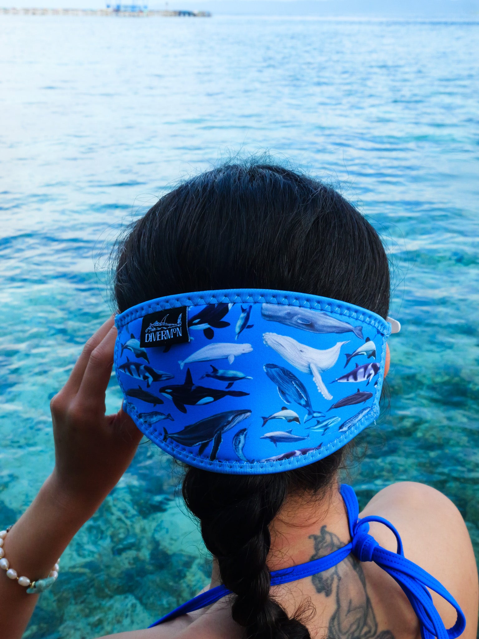 Dark haired woman seen from behind in clear blue water Dolphins, whales and porpoises with a light blue background neoprene mask strap tamer ocean illustration by Diver Mon Art 