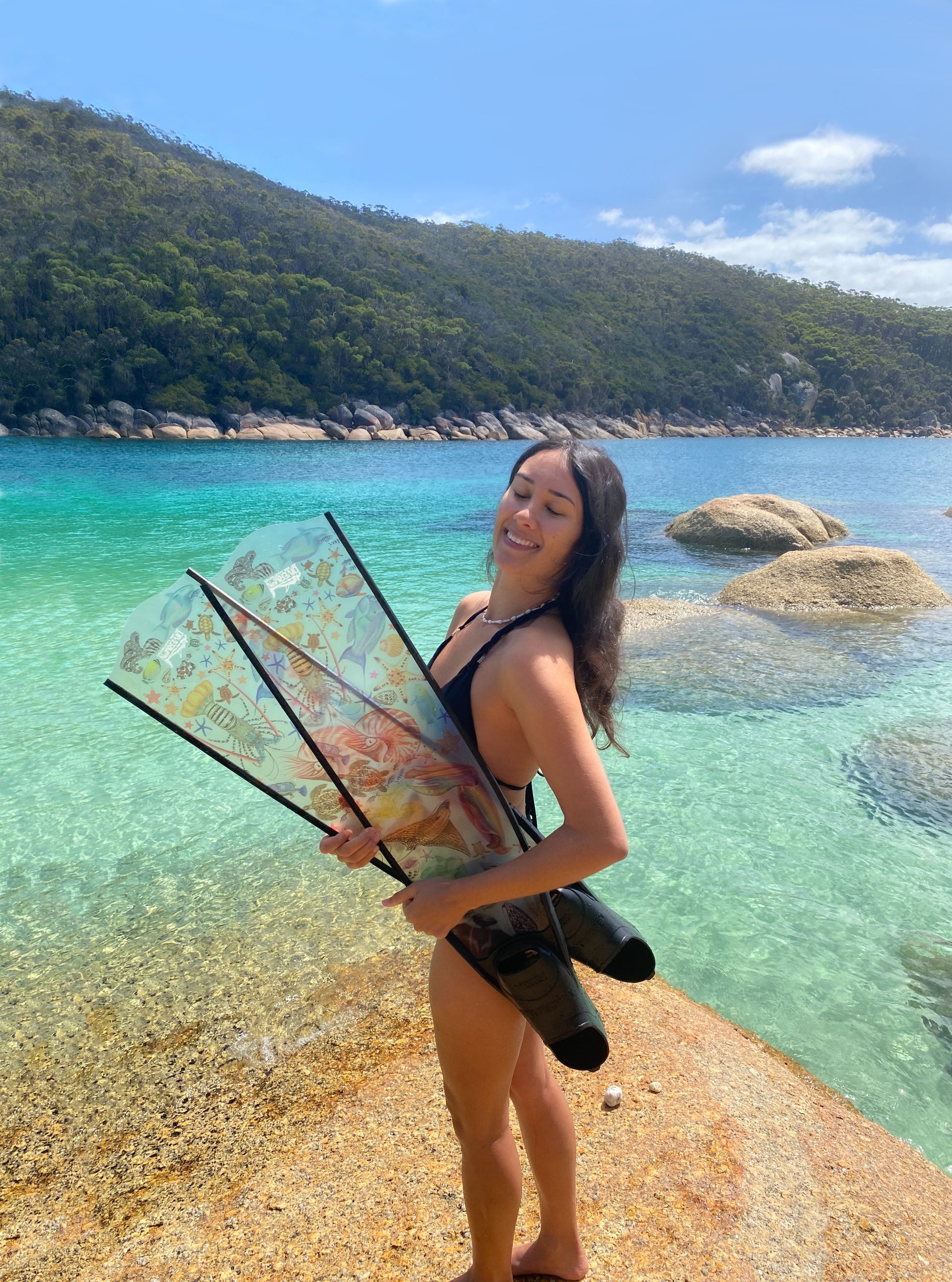 Divermon holding her rainbow design freediving fins with marine illustrations