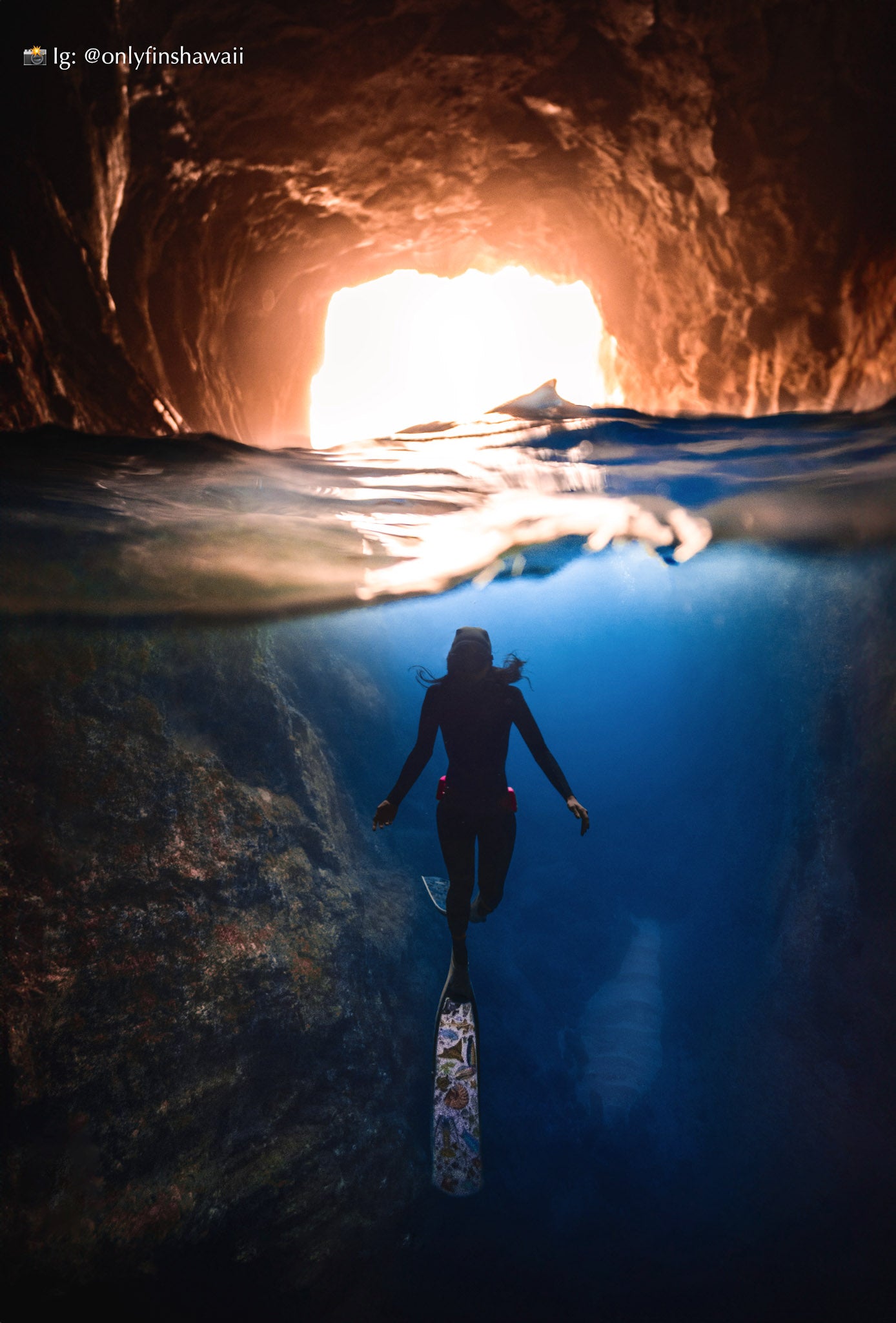 Woman wearing divermon rainbow freediving fins in a cave with sunlight filtering through @onlyfinshawaii