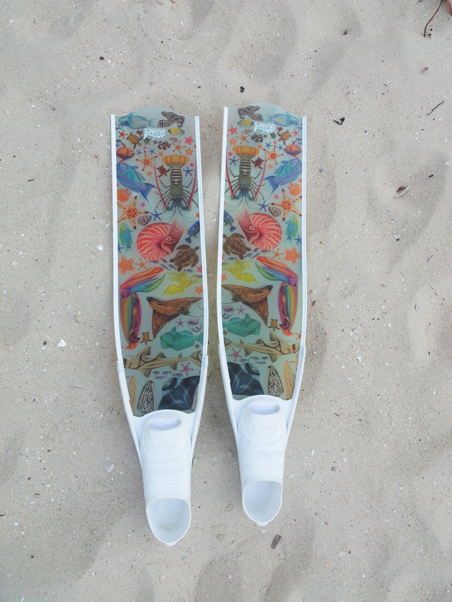Colourful freediving fins with marine illustrations by divermon on a sandy background