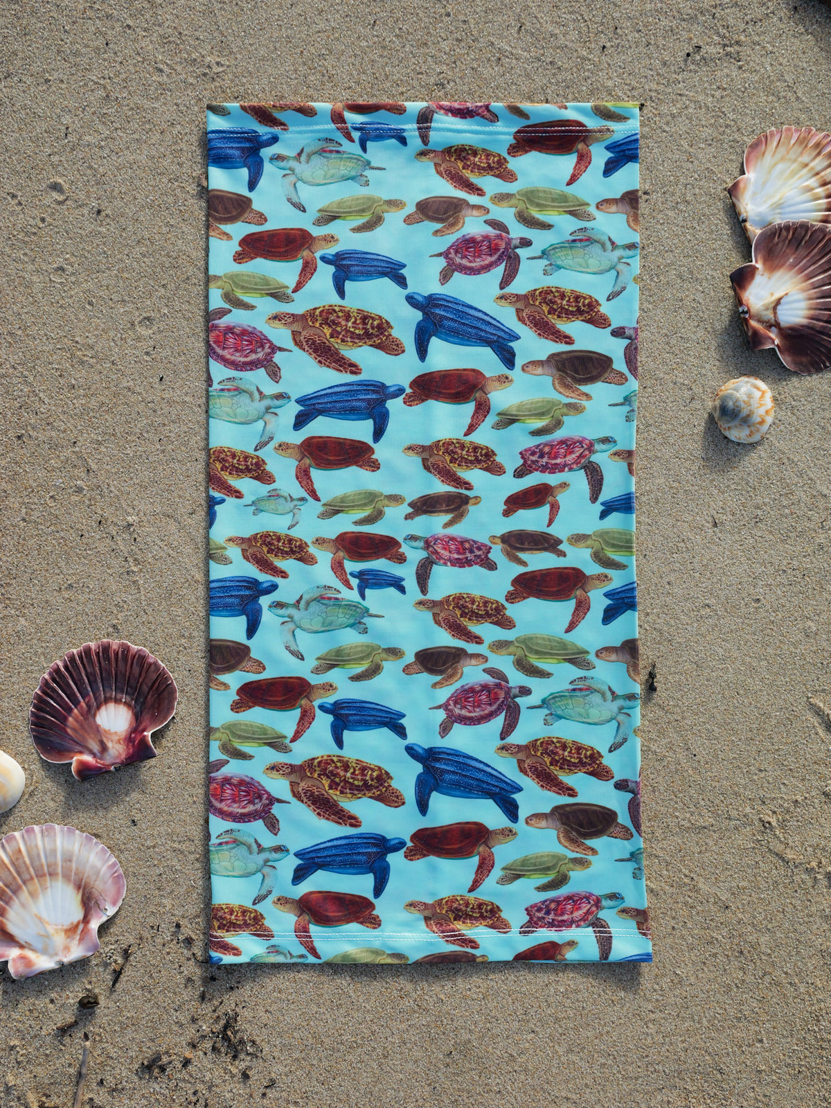 Mini turtles green UV gaiter buff design shown laid out close up in great detail shells sand background made from recycled polyester-spandex ocean illustration by Diver Mon Art