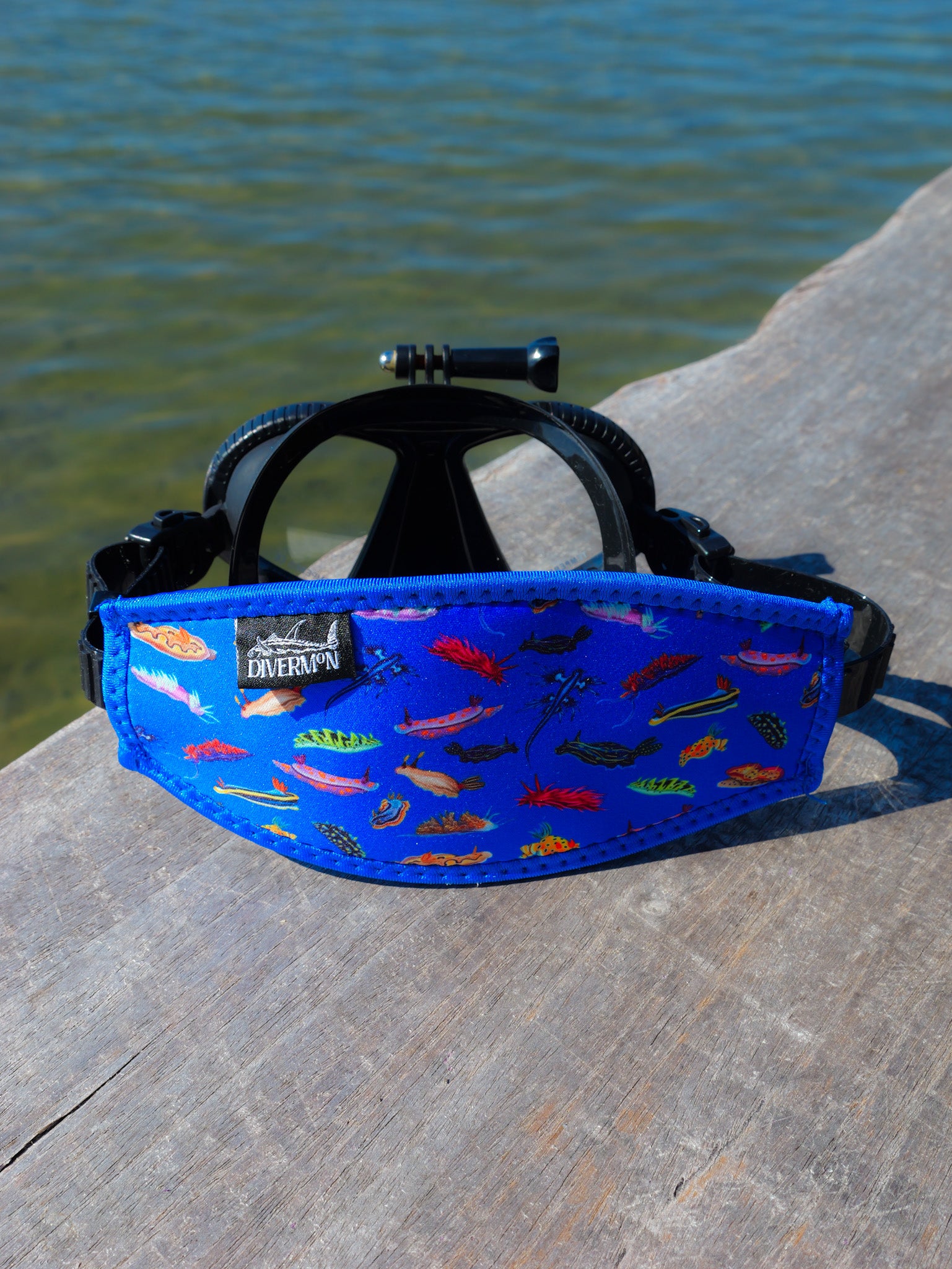 Nudibranch Blue neoprene mask tamer design by Diver Mon Art shown with mask in front of clear water 