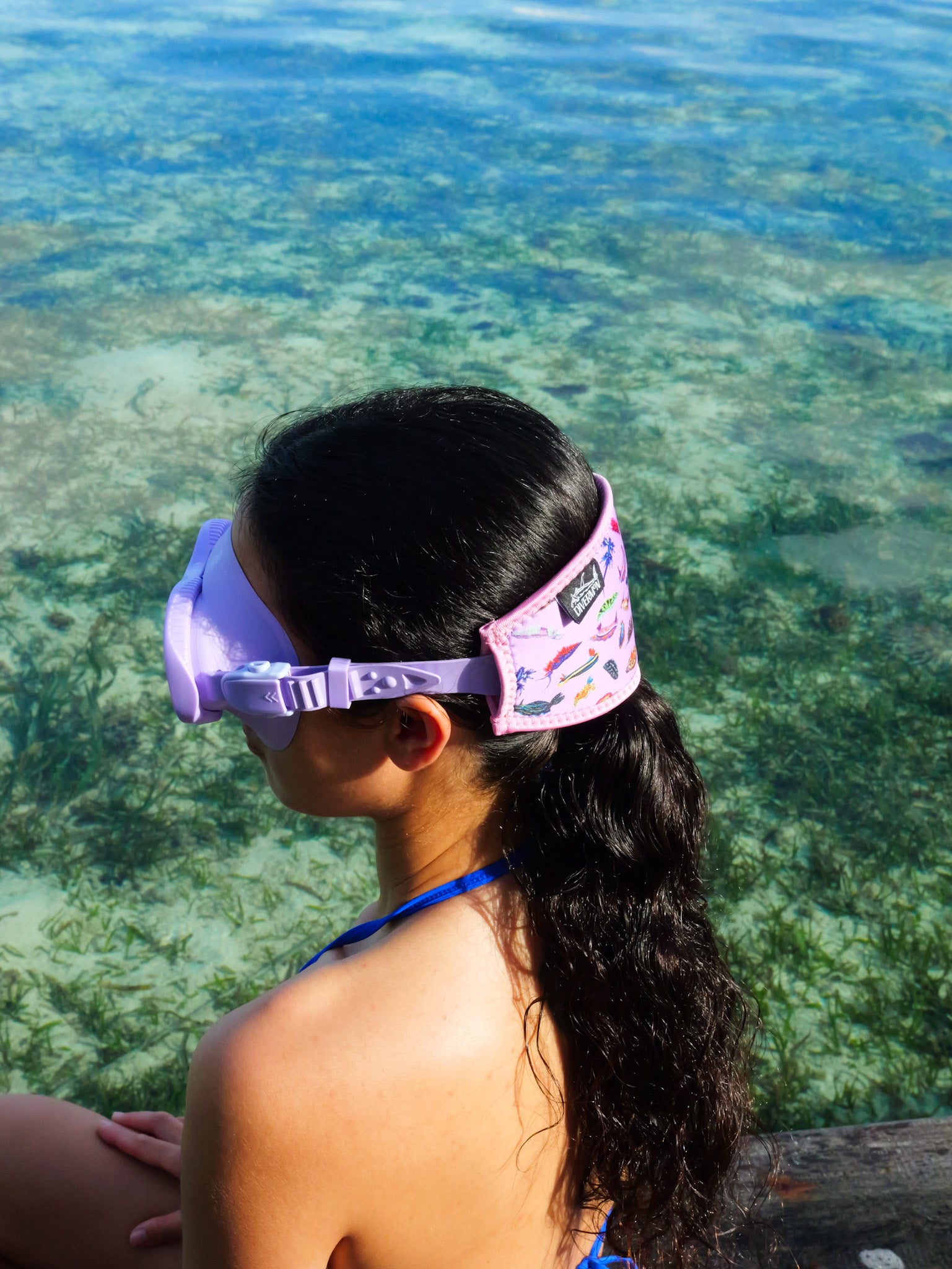 Dark haired woman shown from a side view in blue clear water close up nudibranch pink design neoprene mask strap tamer ocean illustration by Diver Mon Art