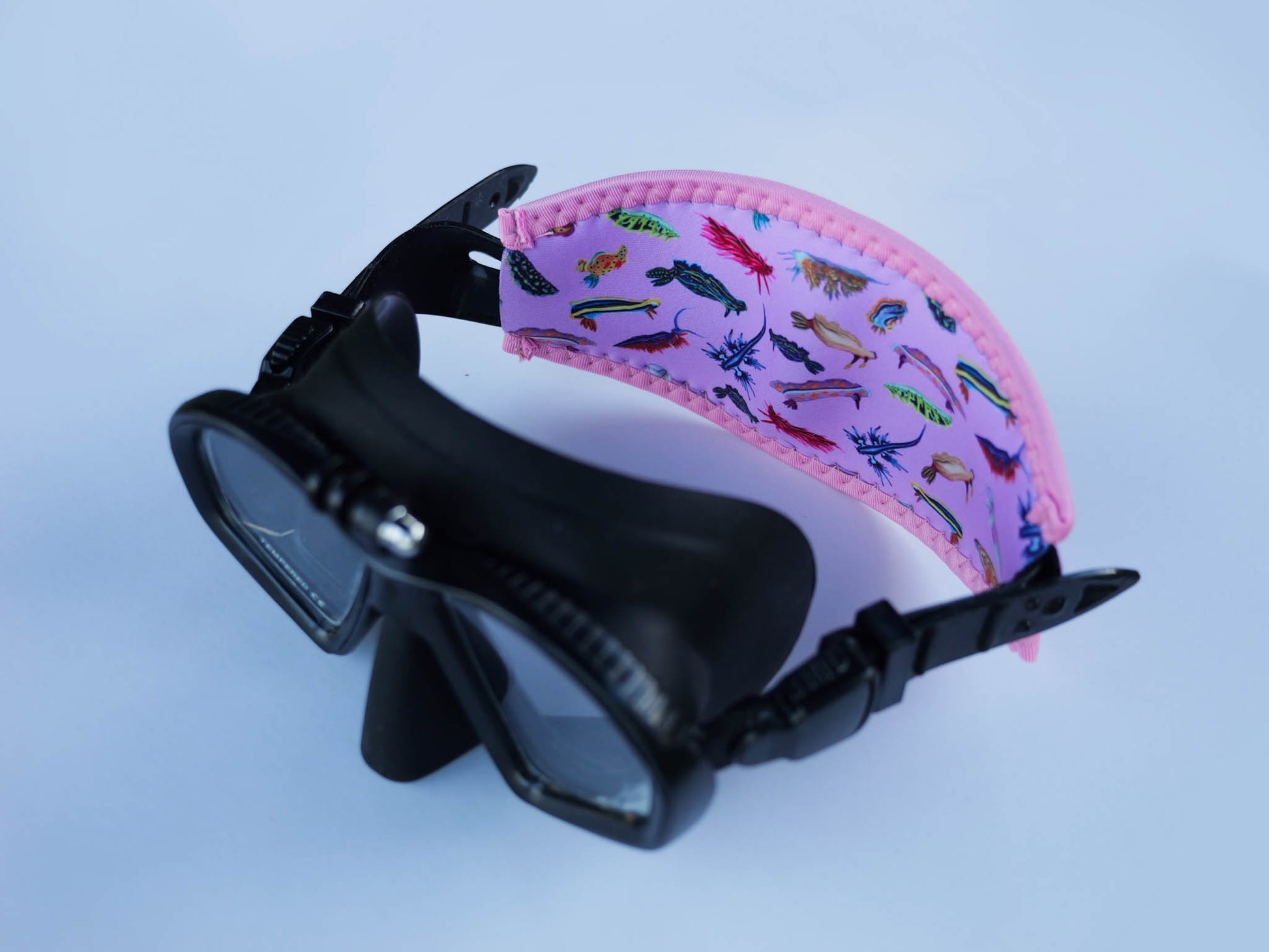 Side view of nudibranch pink neoprene mask tamer by Diver Mon Art shown with fitted to mask 