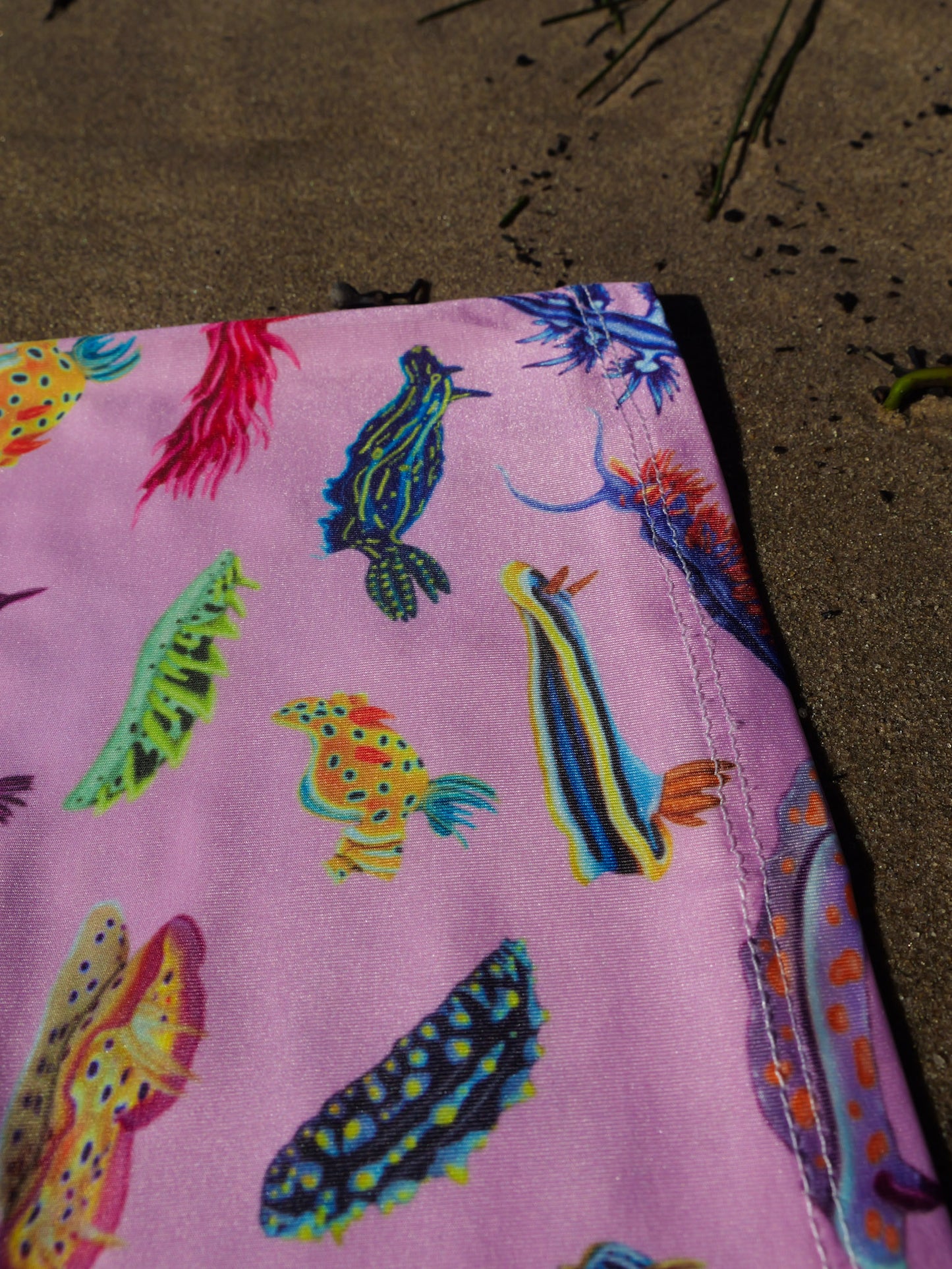 Nudibranch pink UV gaiter buff design shown bottom right close up in great detail sand background made from recycled polyester-spandex ocean illustration by Diver Mon Art