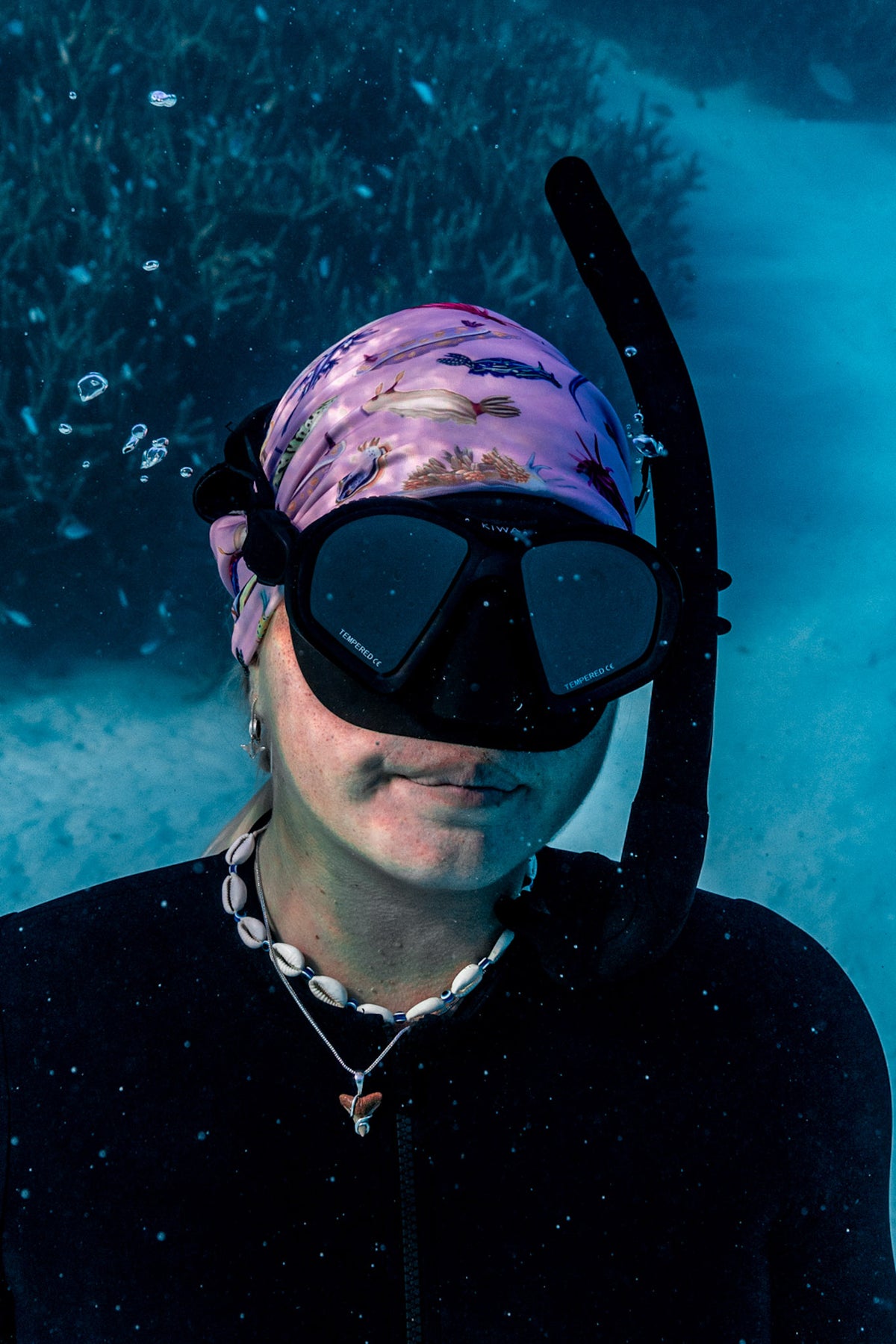 Blonde haired women shown close up great detail underwater clear blue water wearing nudibranch pink UV gaiter buff design made from recycled polyester-spandex ocean illustration by Diver Mon Art