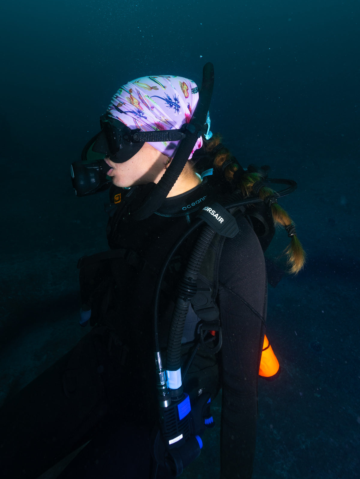 Scuba diver shown side view underwater wearing nudibranch pink UV gaiter buff design made from recycled polyester-spandex ocean illustration by Diver Mon Art