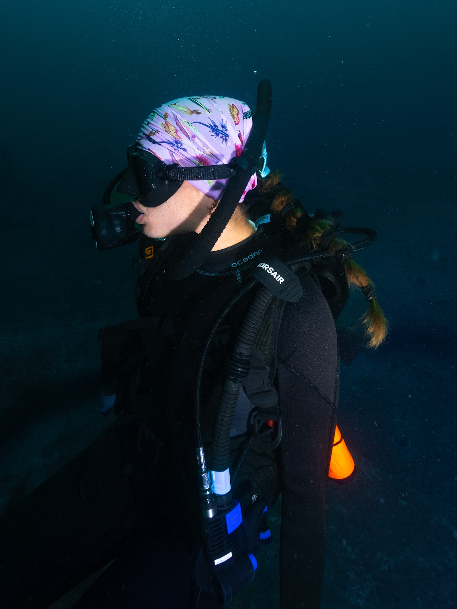 Scuba diver shown side view underwater wearing nudibranch pink UV gaiter buff design made from recycled polyester-spandex ocean illustration by Diver Mon Art