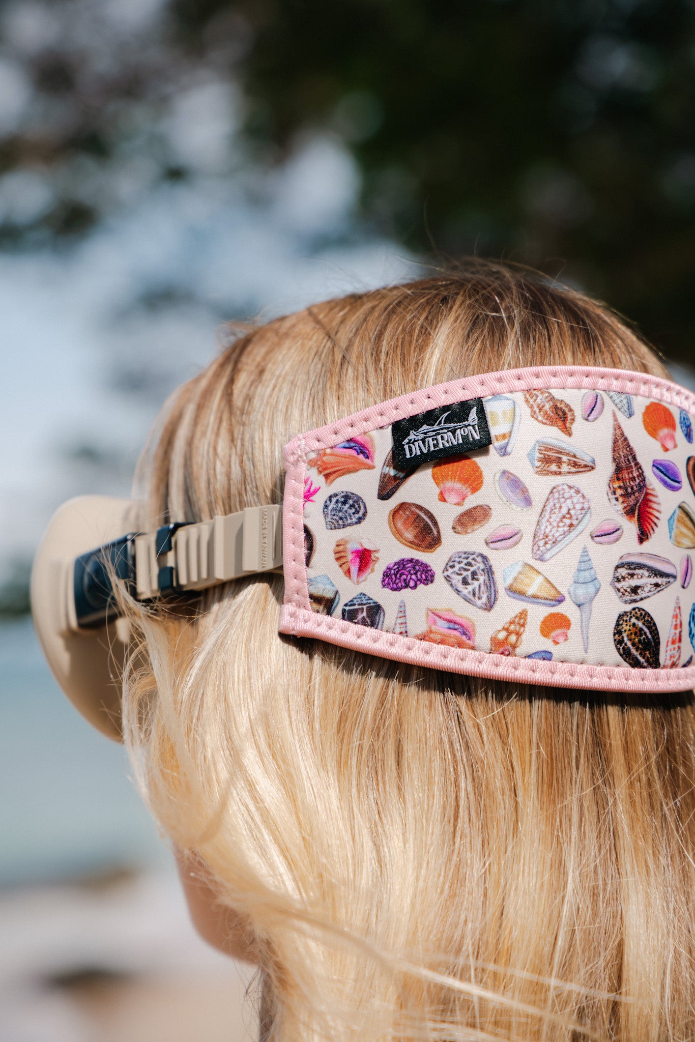 Person wearing a colorful Diver Mon Art neoprene mask tamer with shell pattern 