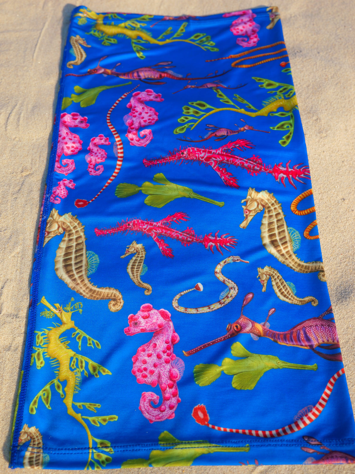 Seahorse dark blue UV gaiter buff design shown laid out close up in detail sand background made from recycled polyester-spandex ocean illustration by Diver Mon Art