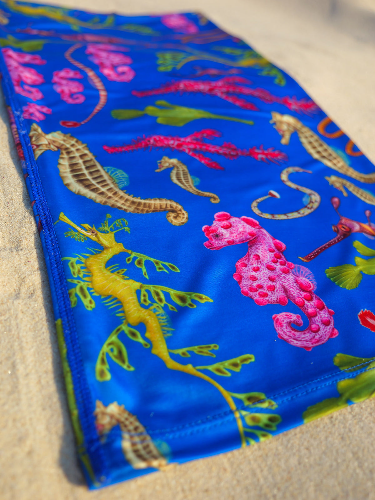 Seahorse dark blue UV gaiter buff design shown bottom left corner close up in great detail sand background made from recycled polyester-spandex ocean illustration by Diver Mon Art