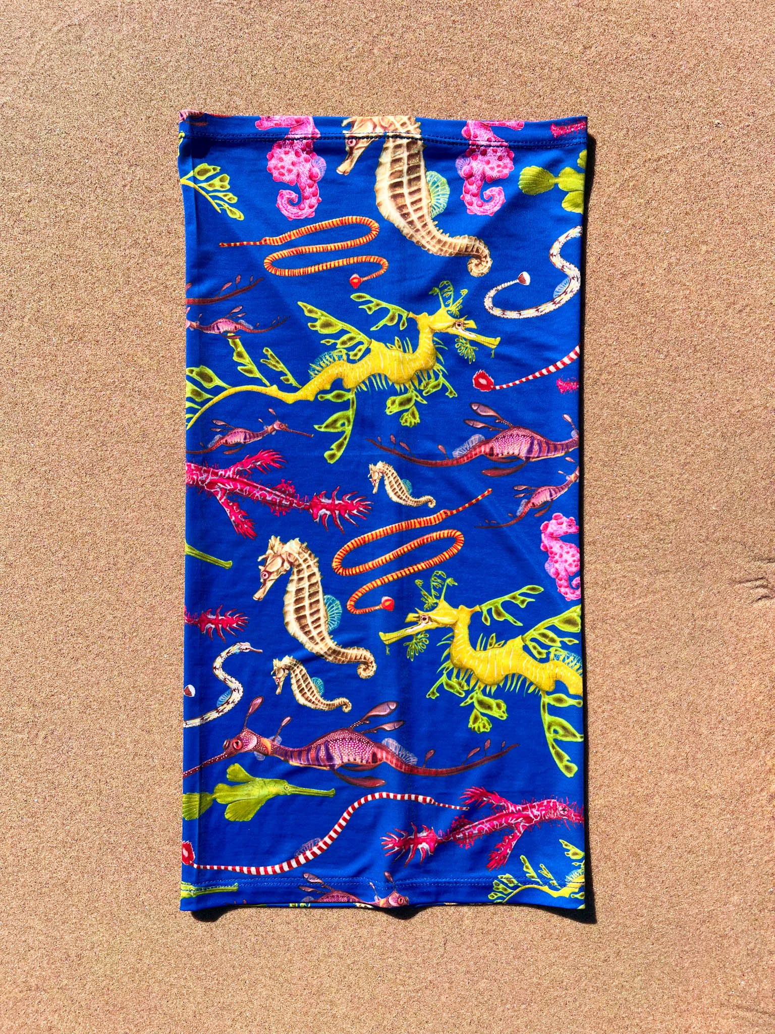 Seahorse dark blue UV gaiter buff design shown laid out close up in great detail sand background made from recycled polyester-spandex ocean illustration by Diver Mon Art