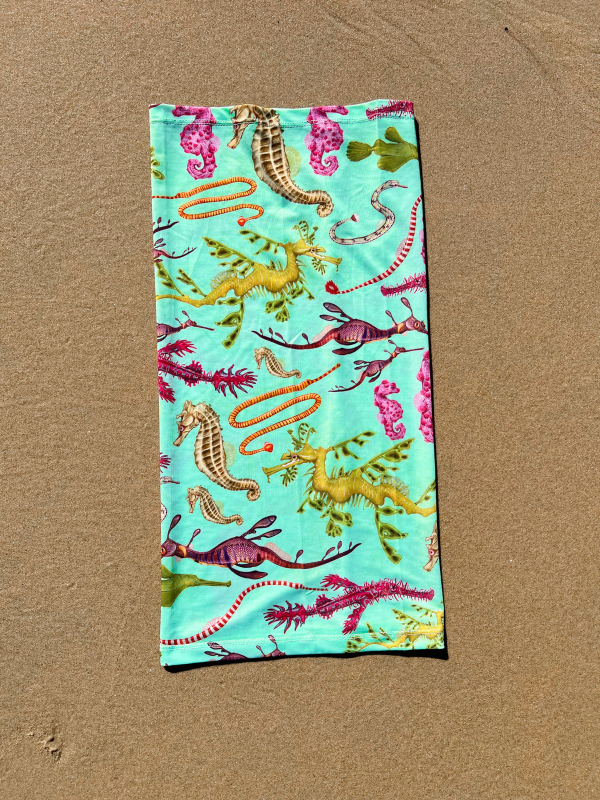 Seahorse green UV gaiter buff design shown laid out full length close up in great detail sand background made from recycled polyester-spandex ocean illustration by Diver Mon Art