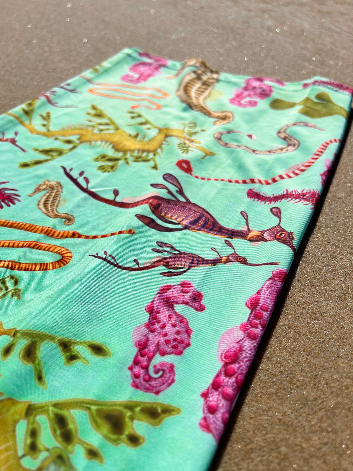 Seahorse green UV gaiter buff design shown bottom right close up in great detail sand background made from recycled polyester-spandex ocean illustration by Diver Mon Art