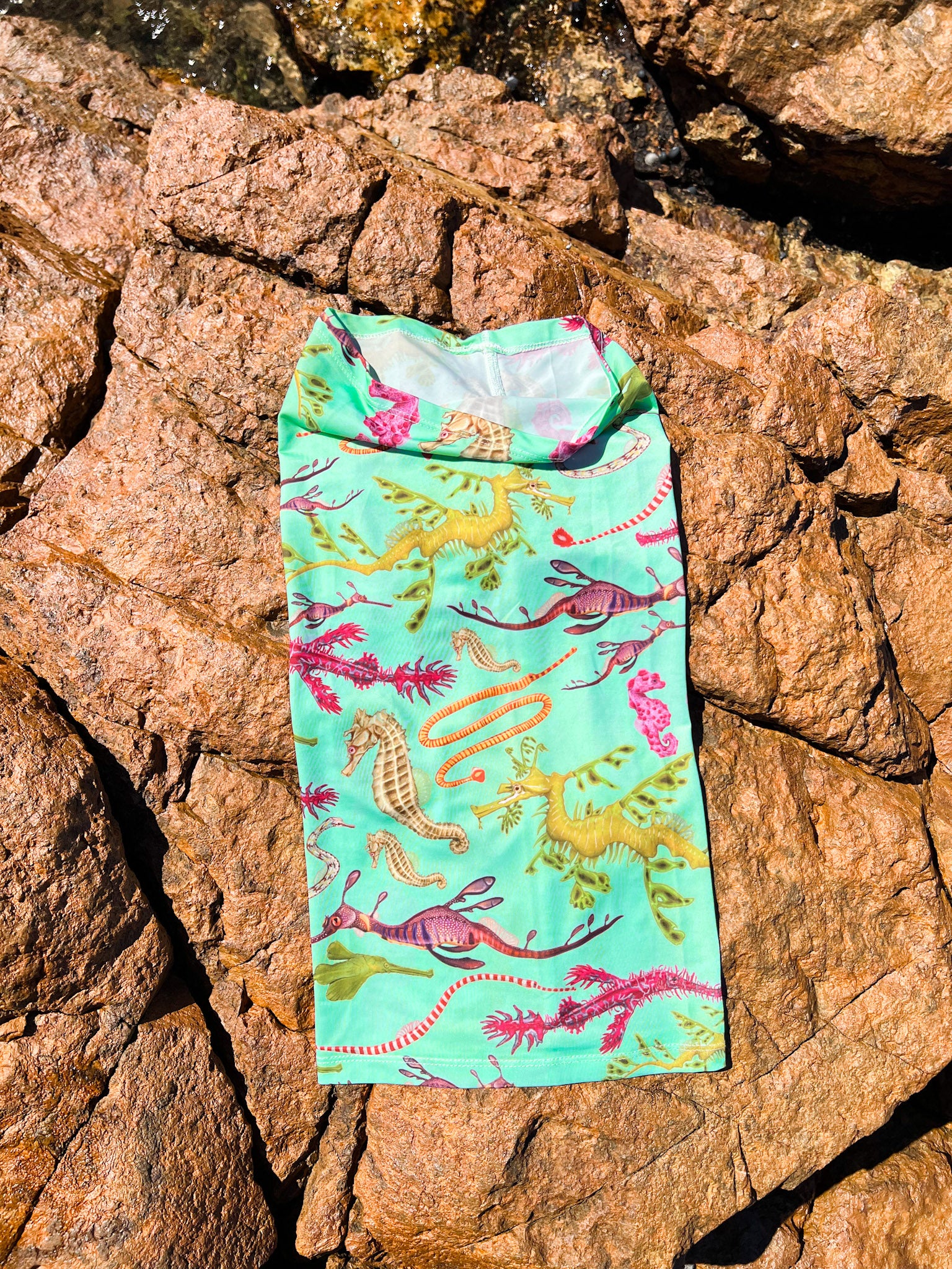 Seahorse green UV gaiter buff design shown laid out on a rock in great detail made from recycled polyester-spandex ocean illustration by Diver Mon Art