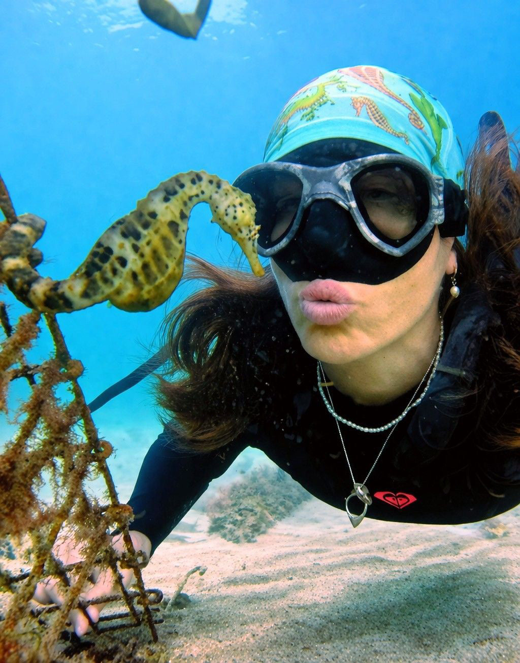 Dark haired women shown in clear blue underwater posing with a 