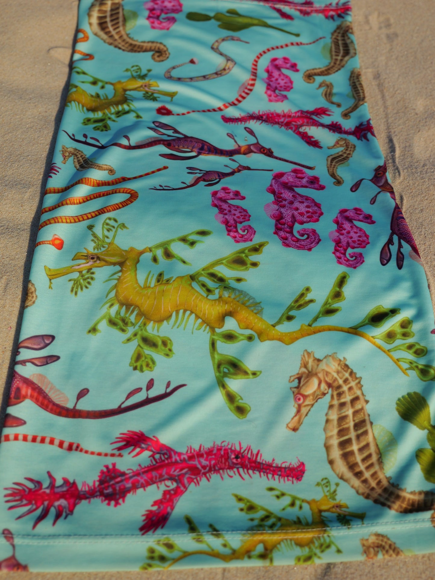 Seahorse green UV gaiter buff design shown laid out full length close up in great detail sand background made from recycled polyester-spandex ocean illustration by Diver Mon Art