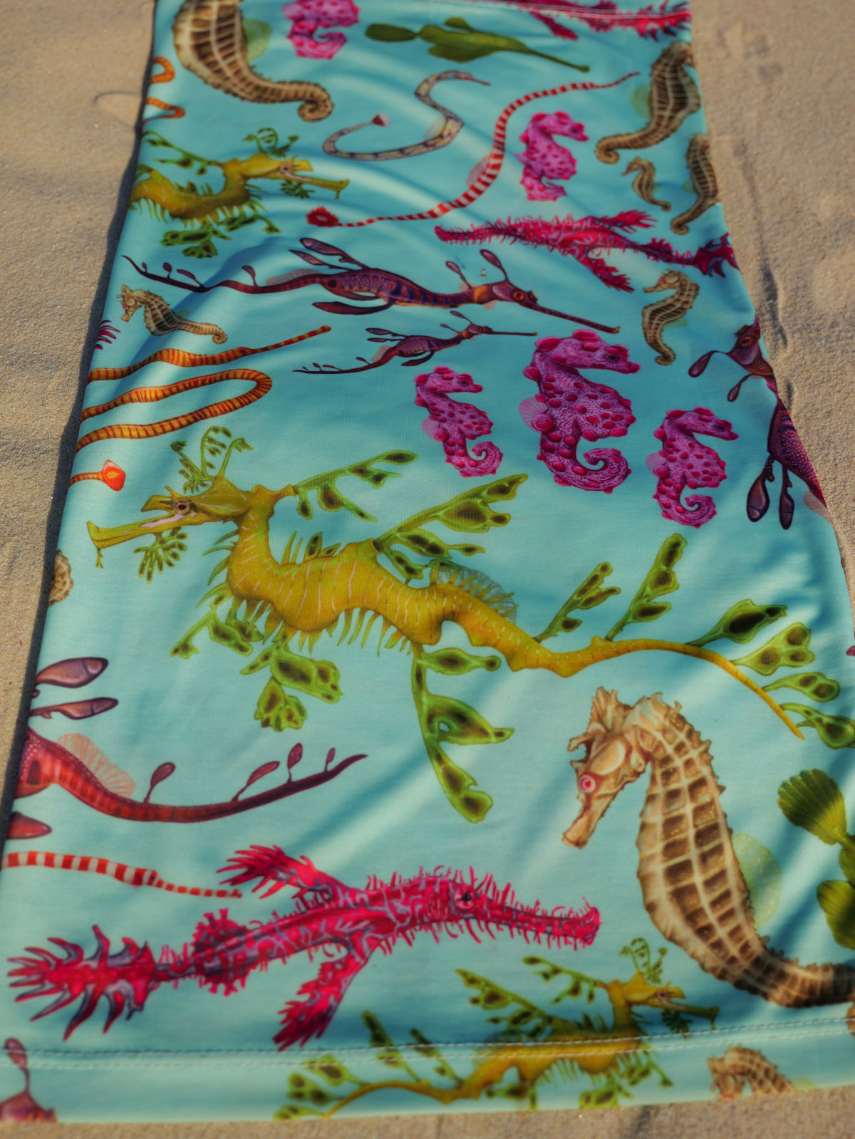 Seahorse green UV gaiter buff design shown laid out full length close up in great detail sand background made from recycled polyester-spandex ocean illustration by Diver Mon Art