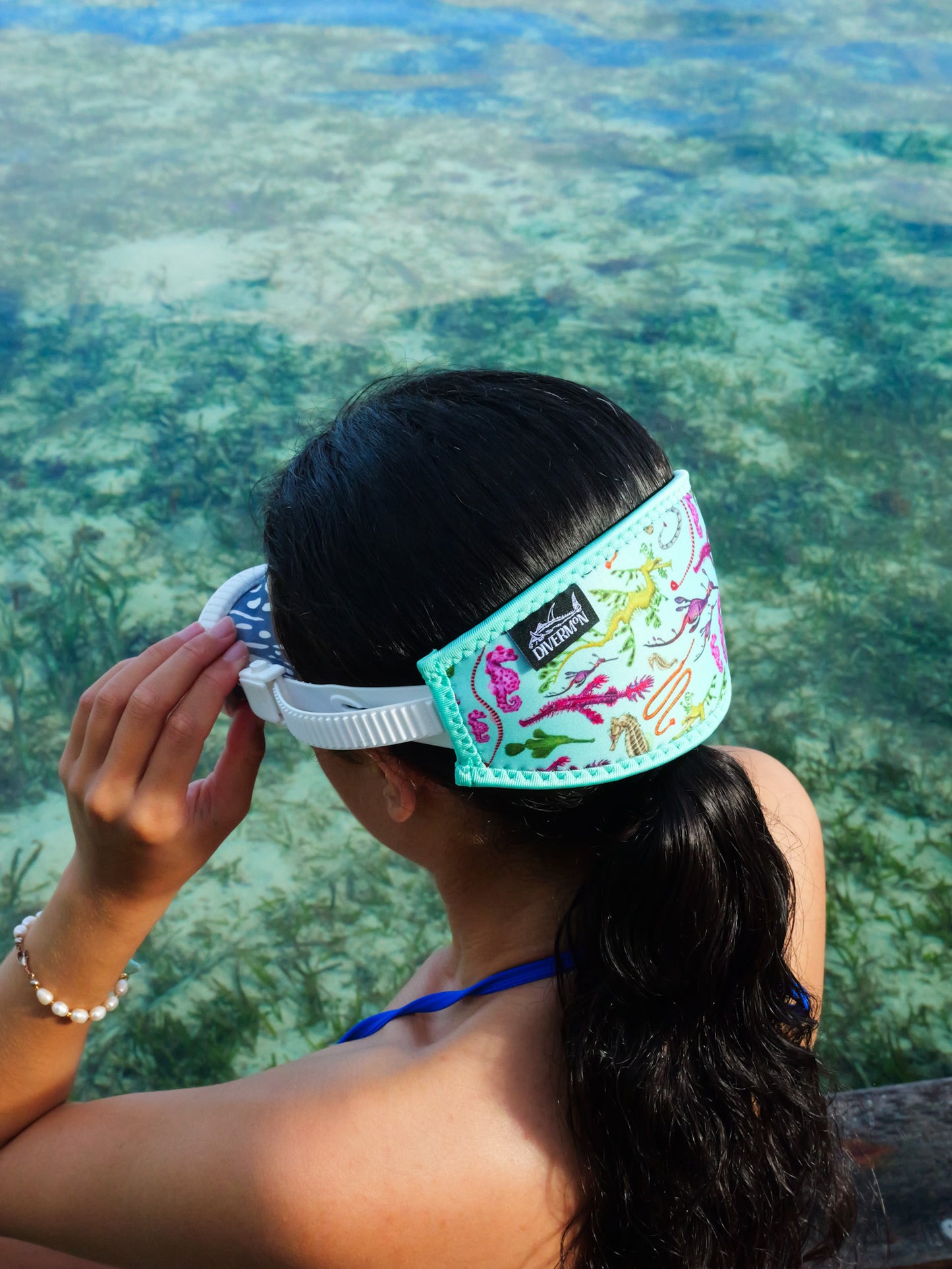 Dark haired woman seen from side view clear blue water seahorse design with green background neoprene mask strap tamer ocean illustration by Diver Mon Art 
