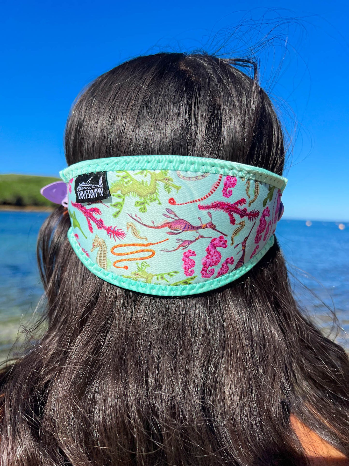 Dark haired woman seen close up from behind at the beach seahorse design with green background neoprene mask strap tamer fitted to mask great detail ocean illustration by Diver Mon Art 