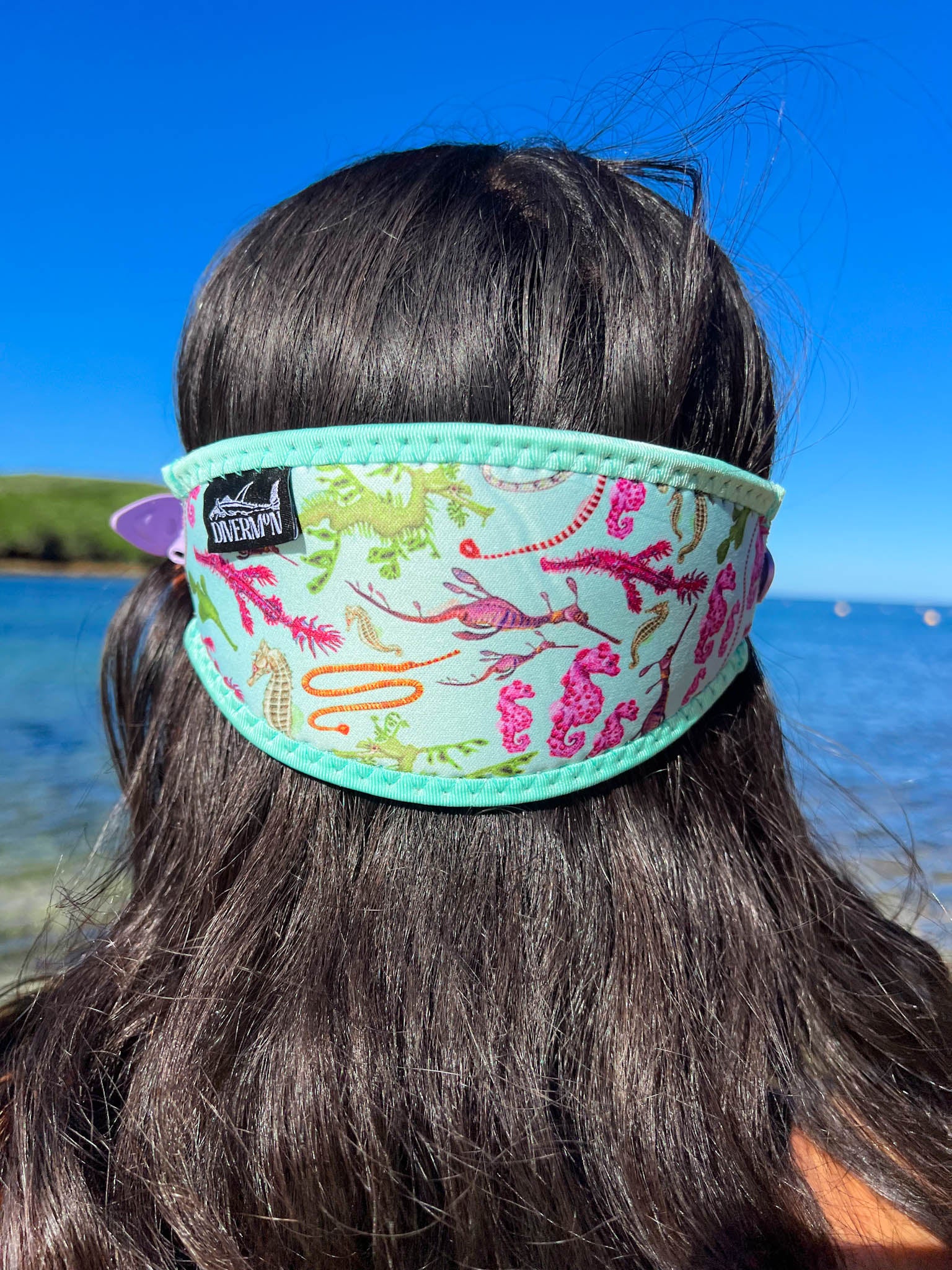 Dark haired woman seen close up from behind at the beach seahorse design with green background neoprene mask strap tamer fitted to mask great detail ocean illustration by Diver Mon Art 