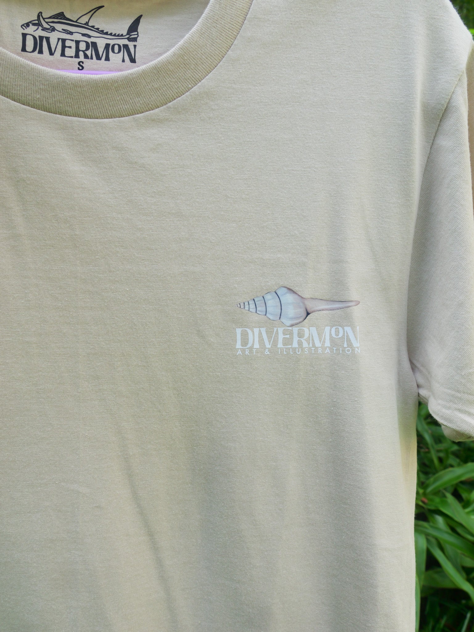 Seashell t shirt featuring ocean shell artwork by Diver Mon Art marine life illustration for beach lovers front logo