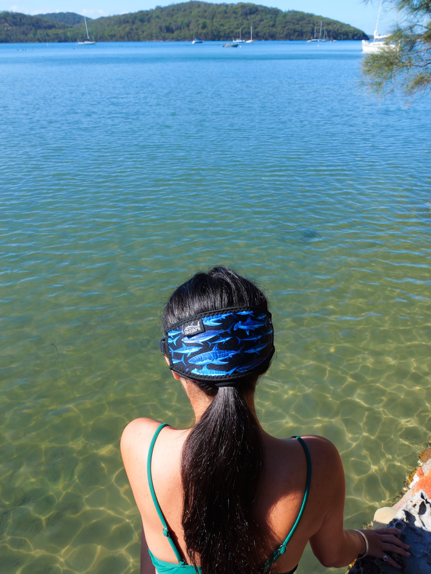 Dark haired woman shown from behind in blue clear water close up shark black design neoprene mask strap tamer ocean illustration by Diver Mon Art  