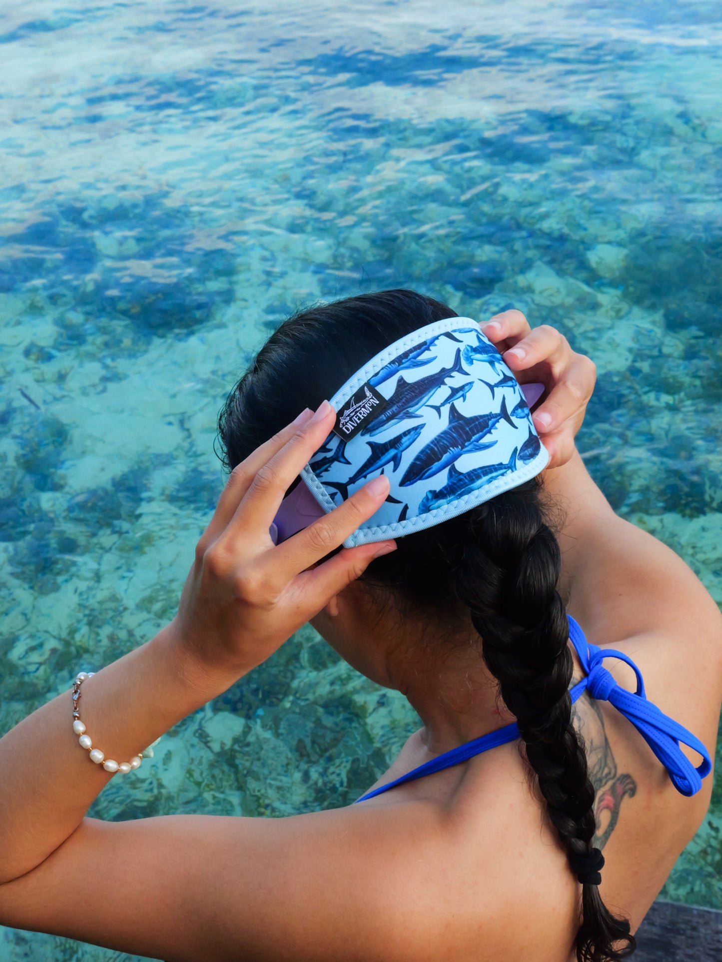 Dark haired woman shown from behind side view fitted to mask in blue clear water close up shark blue design neoprene mask strap tamer ocean illustration by Diver Mon Art  