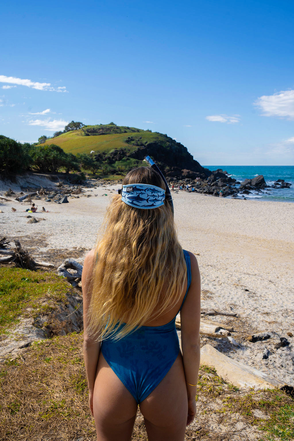 Blonde haired woman seen from behind at the beach with the shark light blue background neoprene mask strap tamer ocean illustration by Diver Mon Art 