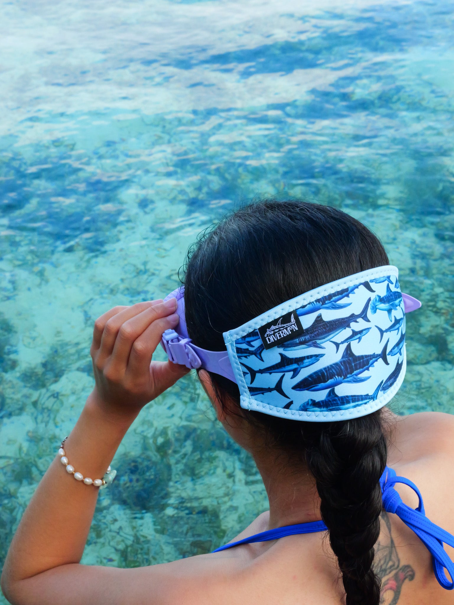 Dark haired woman shown from behind in blue clear water close up with the shark with a light blue background neoprene mask tamer design ocean illustration by Diver Mon Art