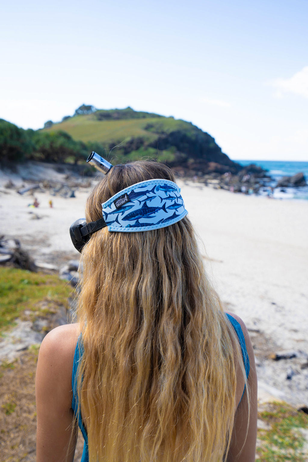 Blonde haired woman seen close up from behind at the beach with the shark light blue background neoprene mask strap tamer ocean illustration by Diver Mon Art 
