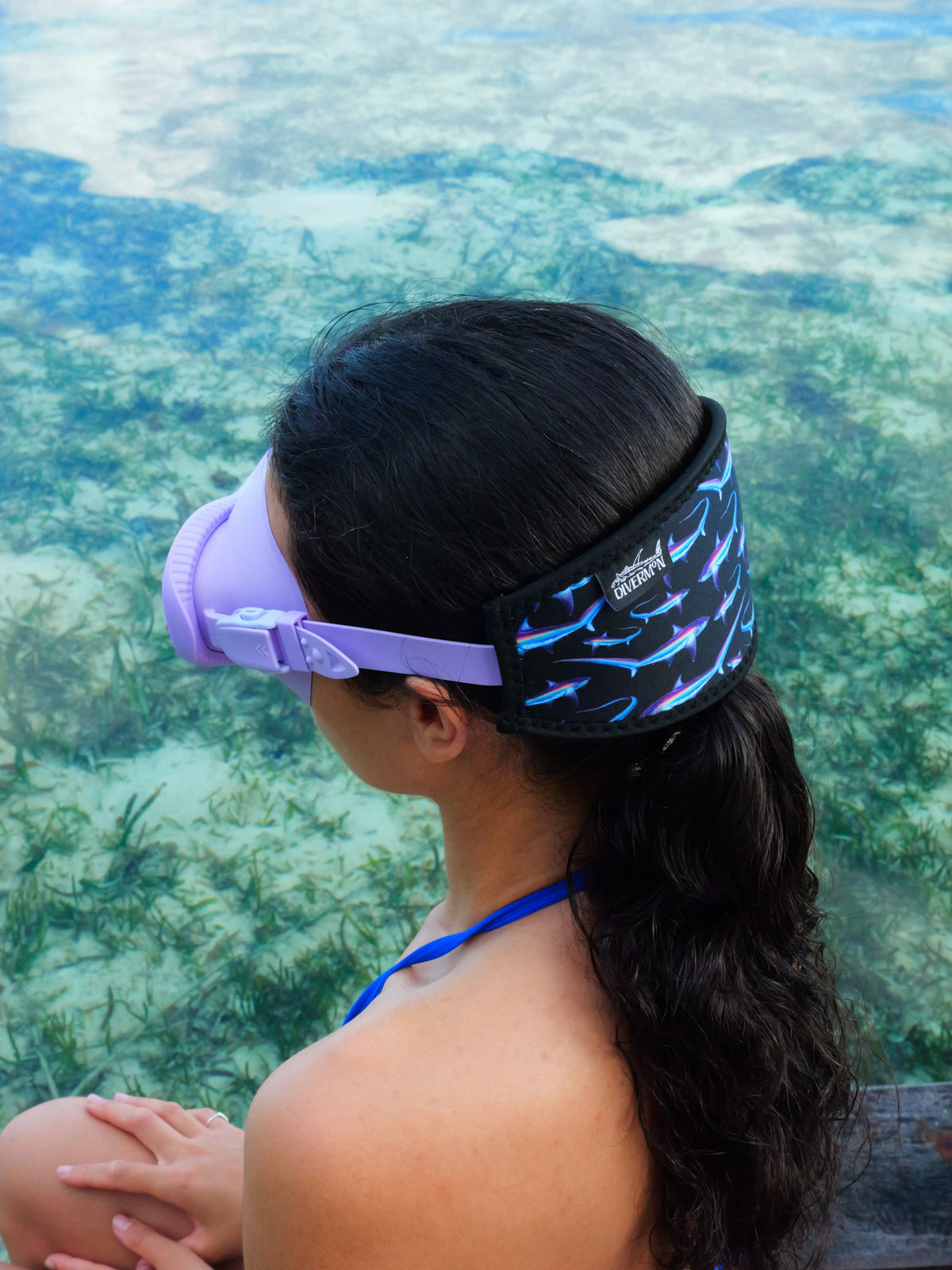 Dark haired woman showing a side view of the black thresher neoprene strap mask tamer in clear blue water ocean illustration by Diver Mon Art 