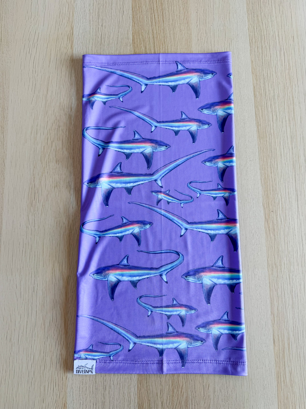 Limited addition thresher purple UV gaiter buff design shown laid out on wooded background made from recycled polyester-spandex ocean illustration by Diver Mon Art 