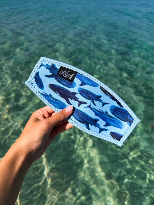 Hand holding whale shark blue neoprene mask tamer design by Diver Mon Art design against a clear blue water background