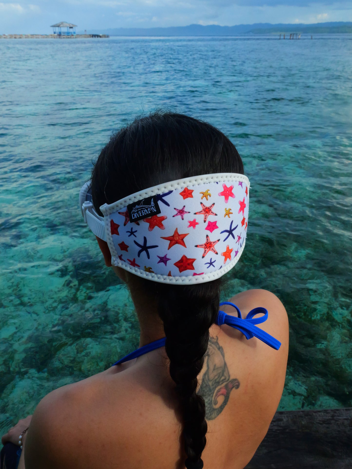 Dark haired woman seen from behind in clear blue water sea star design with white background neoprene mask strap tamer ocean illustration by Diver Mon Art 