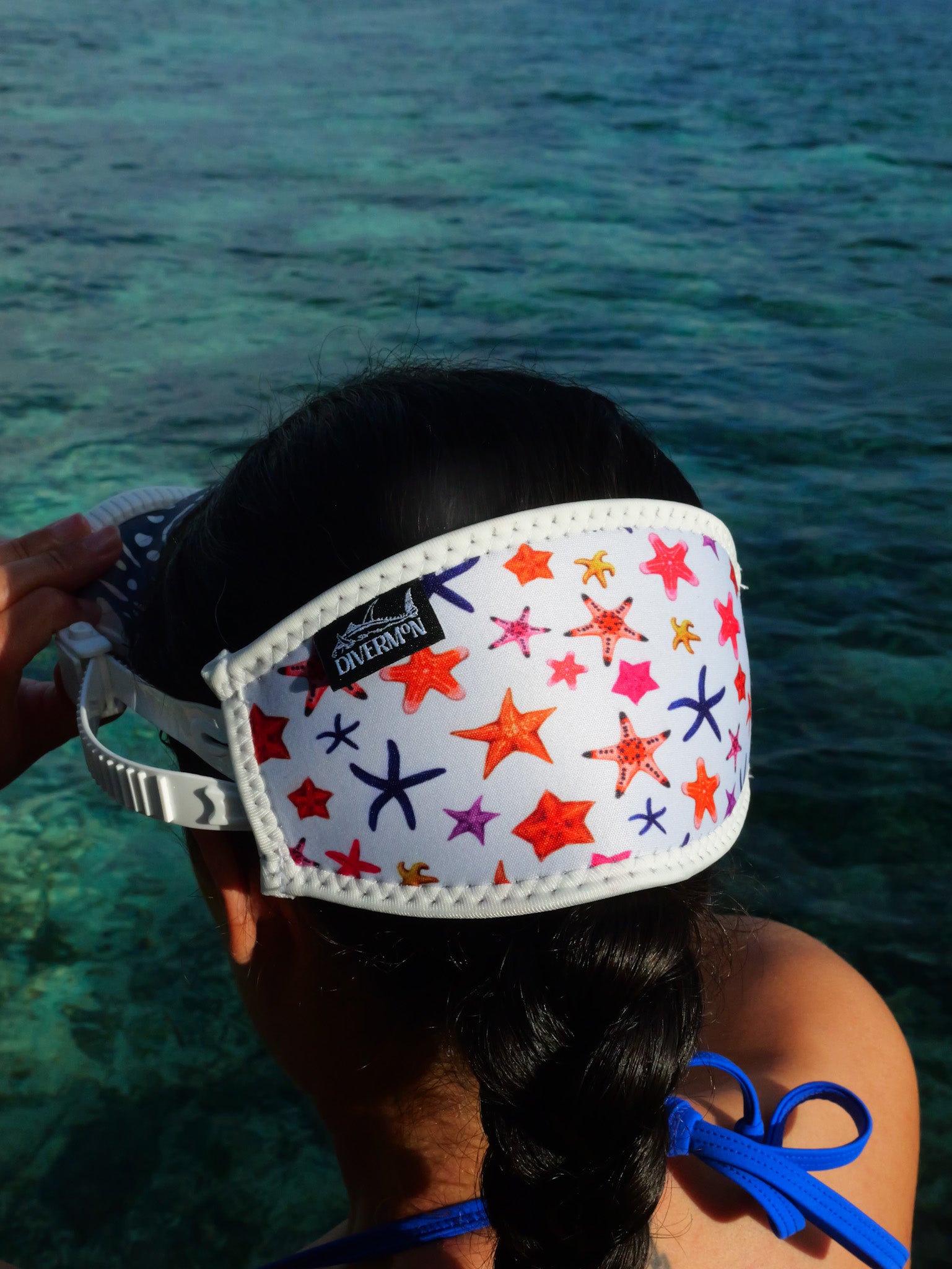 Dark haired woman shown from behind in blue clear water close up in detail white sea star design neoprene mask strap tamer ocean illustration by Diver Mon Art
